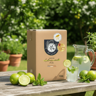 Liqueur de Citron Vert en cubi 5L servie en cocktail frais avec menthe et citrons verts dans un jardin.