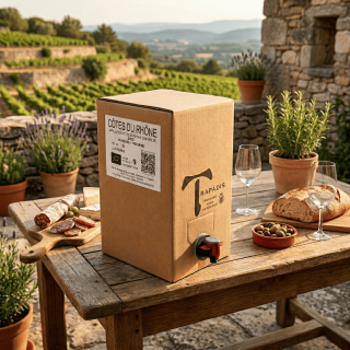Cubi de 5 litres de vin rouge Côtes du Rhône Bio du Domaine du Trapadis prêt à déguster sur une table en bois face aux vignes.