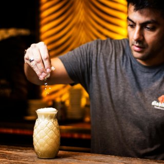 Barman dressant un cocktail Piña Colada dans un verre ananas.