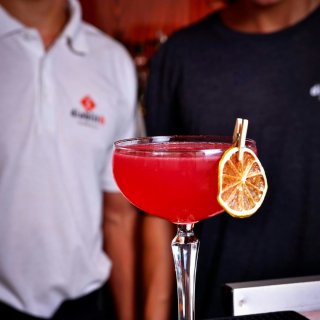 Verre de cocktail Cosmopolitan rouge vif glacé et garni d'un zeste d'orange