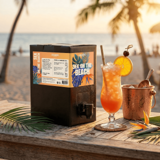 Cubi de cocktail Sex on the Beach de 5L posé sur une table en bois face à la mer