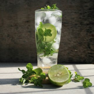 Verre de cocktail Mojito rafraîchissant servi avec des glaçons, une tranche de citron vert et de la menthe fraîche