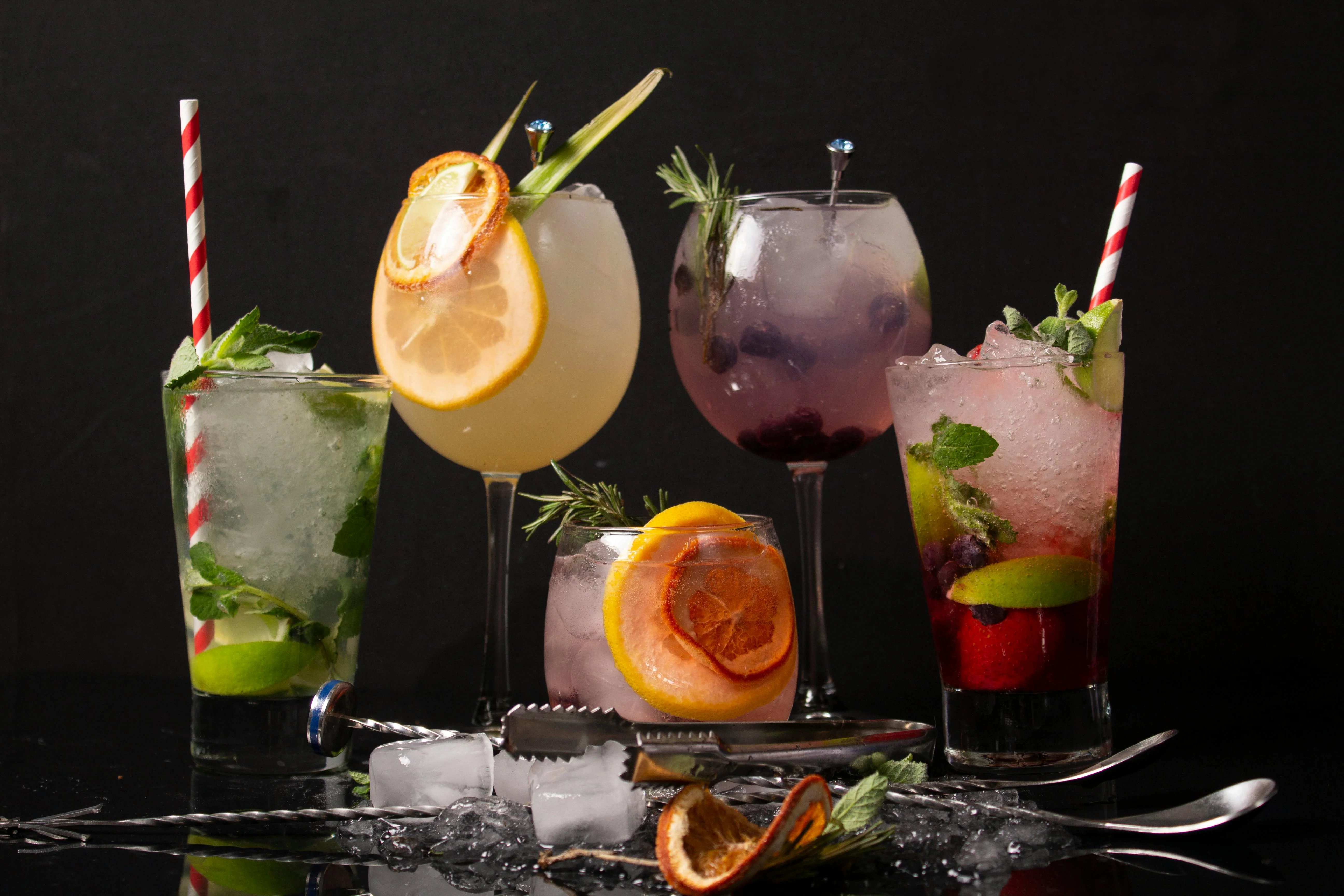 Sélection de cocktails maison garnis de fruits frais, menthe et glace pilée, présentés sur un bar